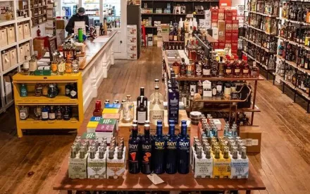 Premium liquor store with backlit shelves displaying Whisky, Beer, Wine, and Vodka-